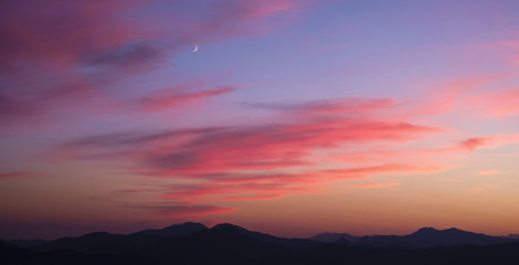 Crescent moon above the hills.