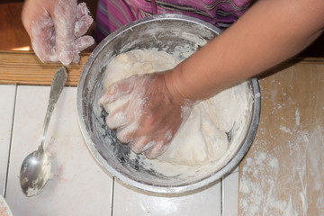 Close up view of baker kneading dough. Hands preparing dough in metal cup.