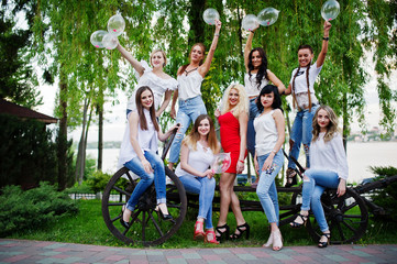 Comany of young women posing outside with inflated condoms at bachelorette party.