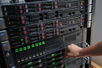 Young woman engineer It  between the server racks in the data center