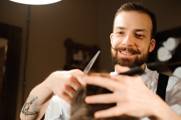 Master cuts hair and beard of men in the barbershop