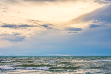 bird flying over surface of green sea waves with mountains on background
