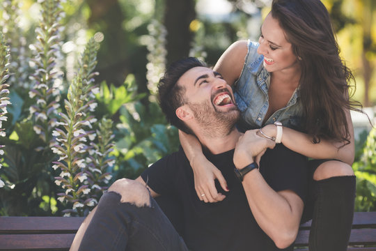 Young couple sitting together outside laughing