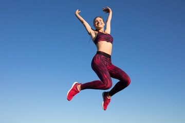 Fototapeta na wymiar Isolated of young happy sportswoman in sportswear jumping and flying at blue sky background. She enjoying summer. Healthy lifestyle concept, sport activity.