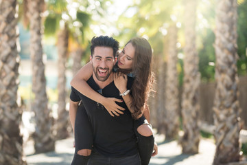 Young happy man giving his girlfriend a piggyback ride