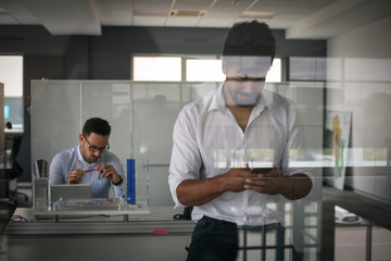 Fototapeta na wymiar African American business person standing in office and using smart phone.