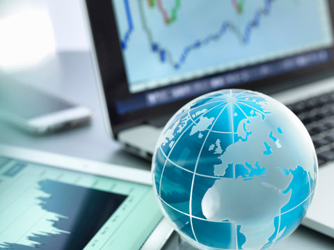 Globe With Digital Tablet, Laptop And Smartphone Showing International Business Graphs