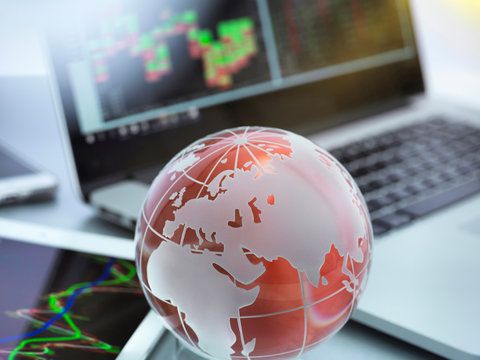 Globe with digital tablet, laptop and smartphone showing international business graphs
