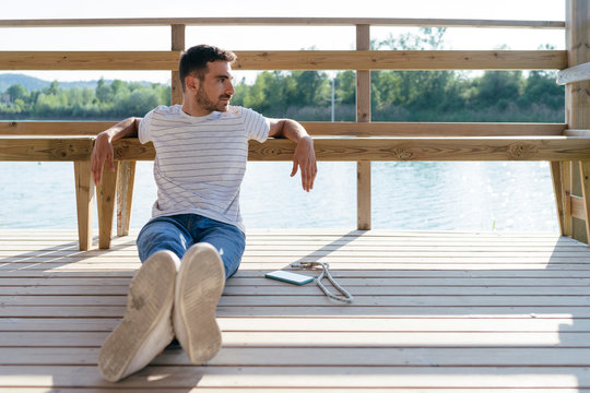 Man relaxing on pier, smartphone beside him