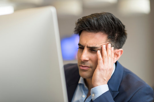 Confused businessman looking at computer in office