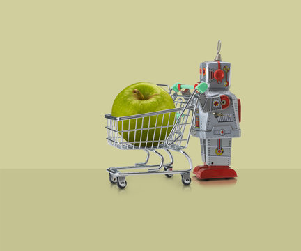 Toy robot pushing miniature shopping trolley with granny smith apple against yellow background