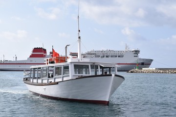 Fototapeta na wymiar Kleine Barke fährt in den Hafen, große Fähren im Hintergrund