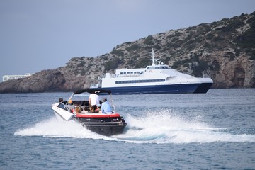 Kleines Motorboot verlässt mit hoher Geschwindigkeit (Full speed) den Hafen, Schnellfähre im Hintergrund