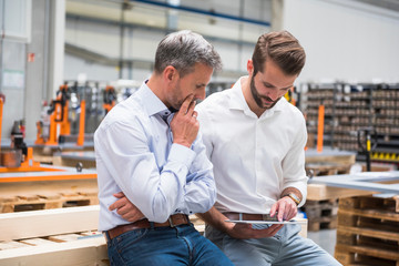 Two engineers looking at digital tablet in engineering factory