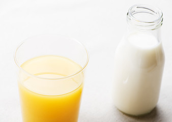 Top view of glass of orange juice and bottle of milk.