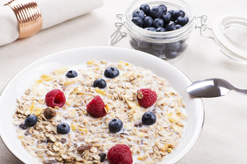 Cereal bowl breakfast with milk, raspberries and blueberries.