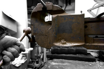 Man using a vice in a workshop with selective colour