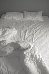 Fototapeta na wymiar Messy white bedding sheets and pillows. black and white tone