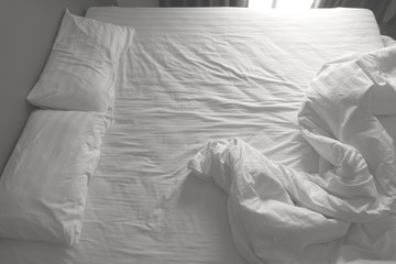 Messy white bedding sheets and pillows. black and white tone