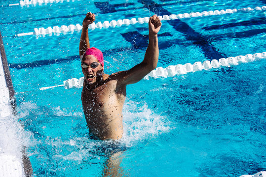 Swimmer in water in pool gesturing triumph