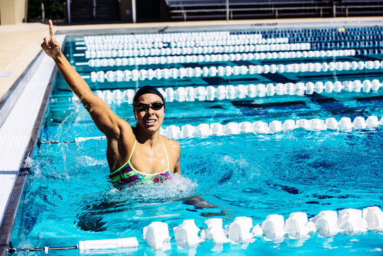 Swimmer in water in pool gesturing triumph