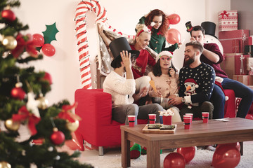 Young adult friends trying on party hats at christmas party