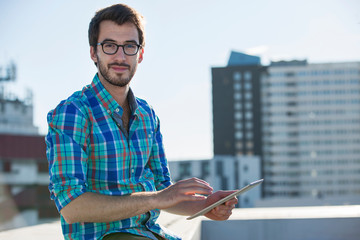 Portrait of man, standing beside office window, using digital tablet
