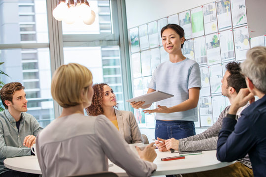 Female digital designer explaining ideas to team at conference table