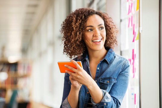 Female digital designer with smartphone looking over her shoulder in office