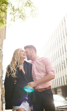 Man in street sharing suit jacket with woman