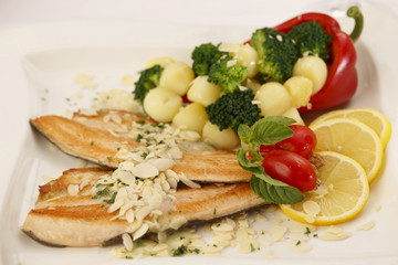 Hake fillet with grilled vegetables arranged on a plate, Traditional dish in elegant setting, Selective focus with soft light