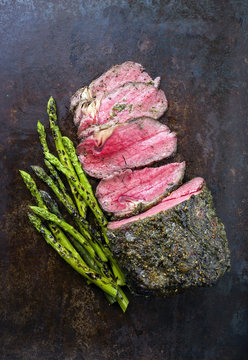 Barbecue Wagyu Roast Beef with green Asparagus as close-up on old board