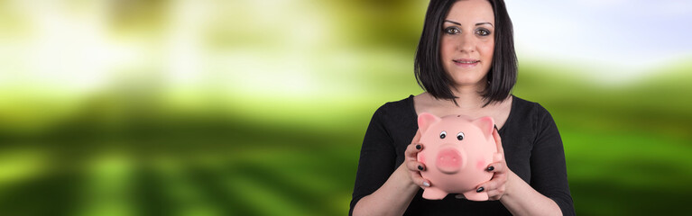 Portrait of young woman holding a piggy bank