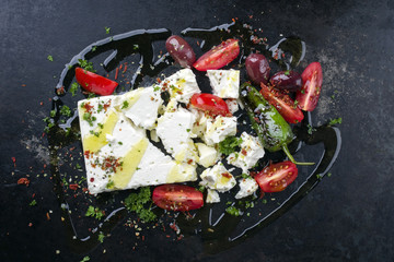 Traditional Greek feta with vegetable as top view on an old rusty bord - obrazy, fototapety, plakaty