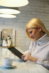 Blonde woman using digital tablet  in the kitchen.