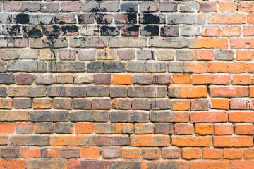 Red old worn brick wall with black spots texture background.