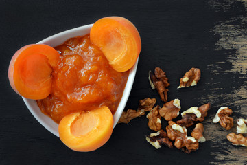 Apricot jam and apricots on black wooden background