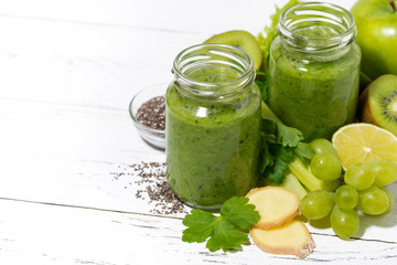 healthy green fruit and vegetable smoothies in jars on white table, top view