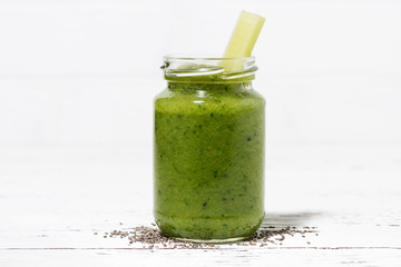 healthy green fruit and vegetable smoothies with chia seeds in jar on white table, closeup