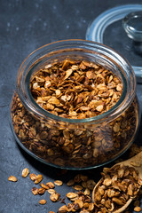 homemade baked granola in a glass jar, top view closeup