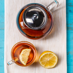 Glass cup of tea with lemon and glass teapot.
