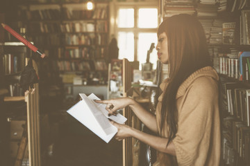 African woman in library. Young woman reading book.