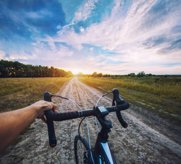 Naklejka na ściany i meble cyclist rides on the meadov dirt road on a Cyclocross bike.