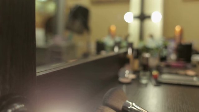 Lamps on mirror in the beauty salon three professional make-up brushes on the table.