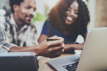 Young smiling african american couple working together at home.Young black man and his girlfriend using laptop at home while sitting at the wooden table. Horizontal,blurred background.