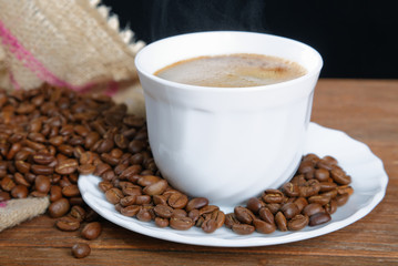 Cup with coffee on the table next to coffee beans