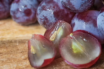 Blue grapes lie on a wooden background. Grapes macro. Grapes with droplets of water. Grapes in a cut. Grapes and wine corks. Blue and green grapes