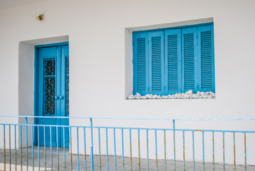 Round white stones on the window white houses with blue doors and window panes. Typical Greek, Sea House