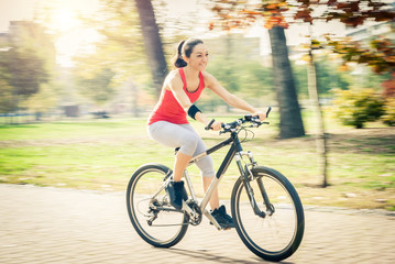 Carefree woman riding bicycle in park having fun on summer afternoon