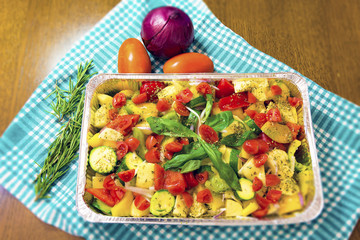 Baked potatoes with zucchini, capers, olives, peppers, cherry tomatoes, basil, oregano. Cooked in aluminum pot.